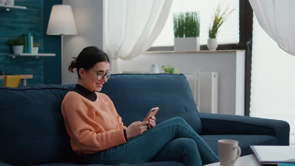 College Student Browsing Internet on Smartphone at Home