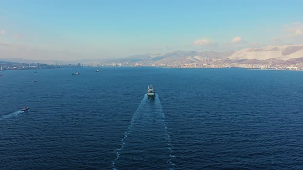 Aerial View Following the Ultra Large Cargo Ship at Sea Leaves Port at Sunset