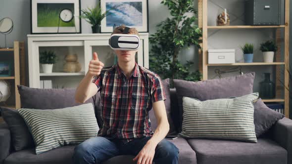 Man with Fair Hair Is Having Fun with Virtual Reality Glasses Moving Hands and Head