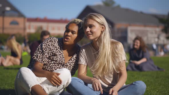 Diverse Girlfriends Sitting in Park on Green Grass Chatting and Relaxing on Break at Work