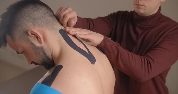 Kinesiologist Sticks Tapes to the Neck of Patient Recovery of an Athlete After Injury Kinesiotapes