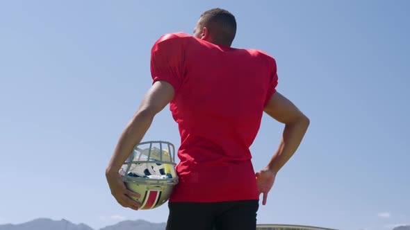 American football player standing with helmet