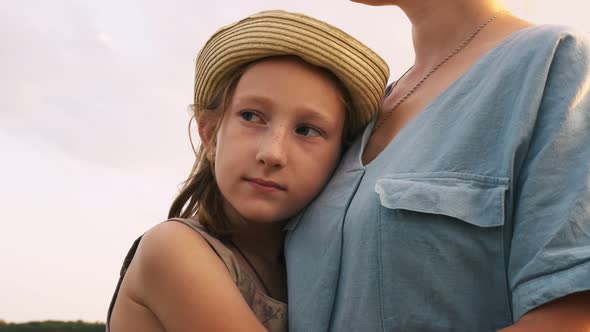 A Beautiful Teenage Girl in a Hat Gently Hugs Her Mother