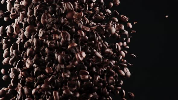 From the Bottom Up Many Black Roasted Coffee Beans Fly Up on a Black Background