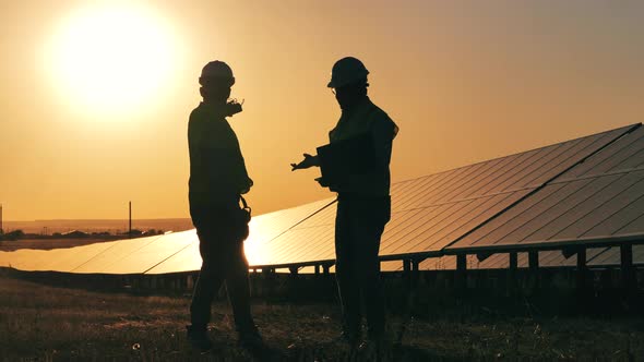 Sunset at the Solar Power Station with Two Workers Talking