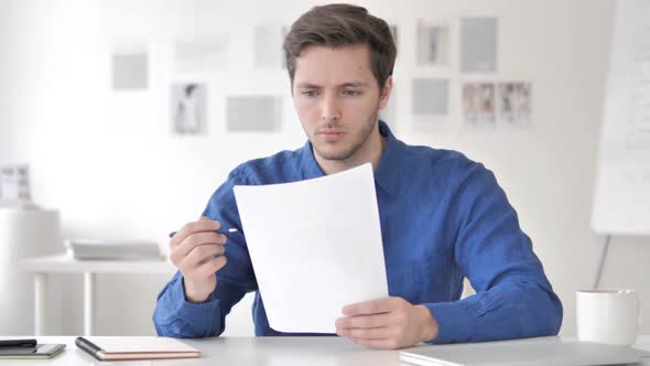 Casual Adult Man Reading Documents in Office