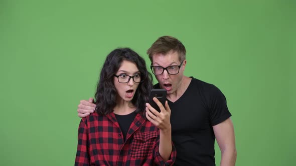 Young Couple Using Phone and Looking Shocked Together