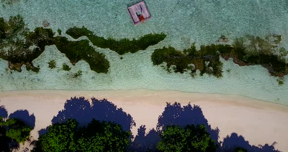 Natural overhead tourism shot of a white paradise beach and blue water background in vibrant 4K