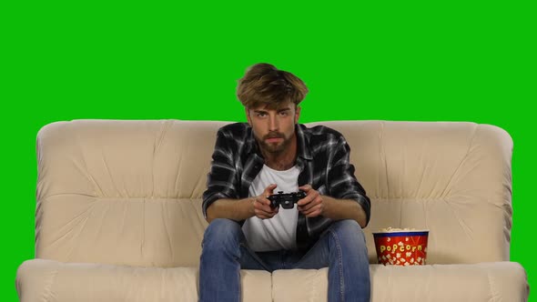 Gamer Is Playing with a Joystick While Eating Popcorn. Green Screen