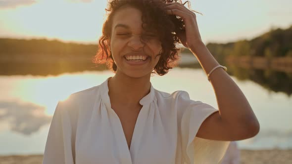 Beautiful Young Black Girl Looking at Camera Standing on a Beach at the Sunset