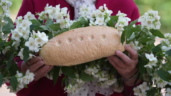 Ukrainian old woman holding bread in her hands