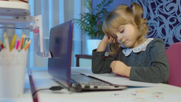 Bored Kid Listening Audio Lesson Studying at Table Using Digital Laptop Computer Doing Homework