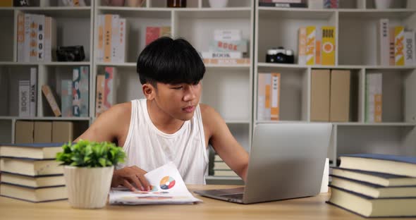 Tired man using laptop and looking document