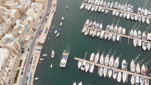 Bird's-eye, panning 4k footage, of a marina along a water channel between two cities of Malta