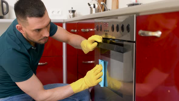 Man with Rag Cleaning Oven Door at Home Kitchen 9