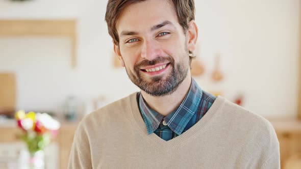 Young Positive Bearded Guy Smiling to Camera Posing at Home Interior with Spring Bouquet Tracking