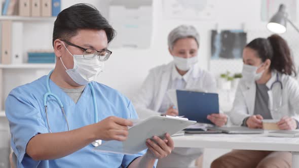 Asian Doctor in Mask Holding Documents