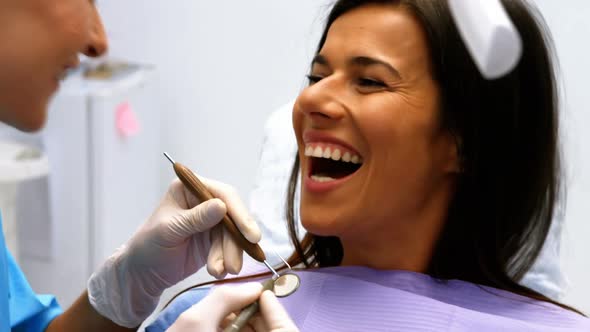 Dentist examining a female patient with tools