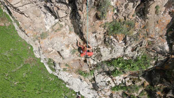 Woman Athlette Climbing on the High Rock in the Mountains