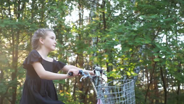 Teenager Girl Rides Bike Past Trees at Back Sunlight Closeup