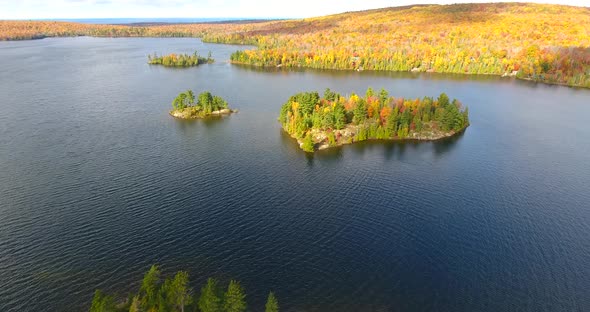 Aerial Over Serene Blue Lake in Michigan with Small Islands During Peak Fall