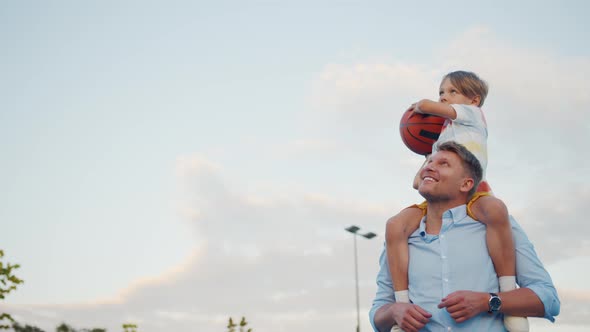 Little boy with dad playing basketball outdoors