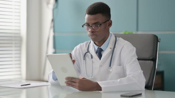Young African Doctor Using Tablet While Sitting in Office
