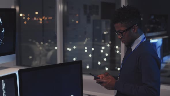 Black Programmer Using Smartphone at Night