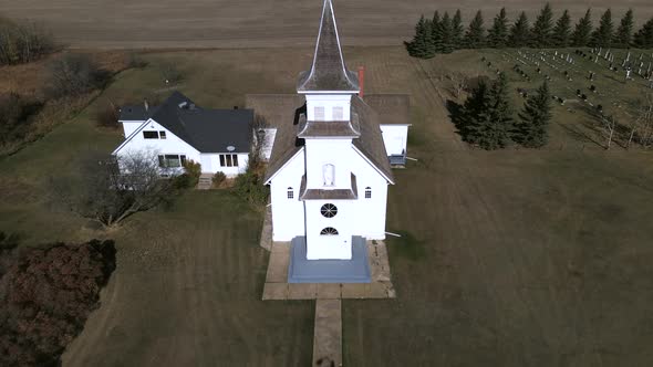 Slow aerial pull backement in 4k revealing beautiful old country church and person walking towards i