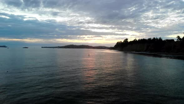 Aerial drone shot in Montecito during a colorful sunset over the Pacific Ocean with a paddle boarder