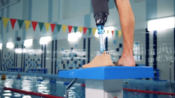 Close Up of a Male Healthy Leg and a Prosthetic One in the Swimming Pool