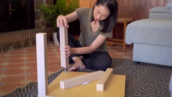 Asian woman assembling table in living room