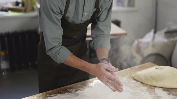 Unrecognizable Male Baker Claps and Scatters White Flour in the Air