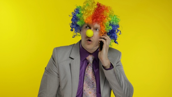 Clown Businessman Entrepreneur Boss Talking on Mobile Phone. Yellow Background