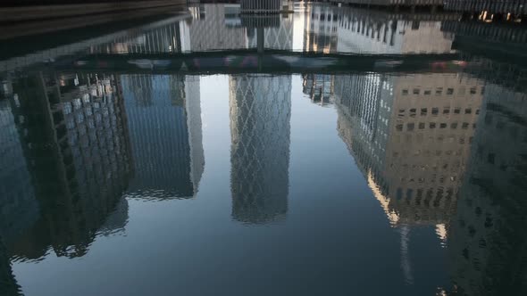 Pan up from Canary Wharf middle dock reflection to Newfoundland tower building
