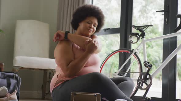 Video of midsection of plus size african american woman in sport clothes stretching at home