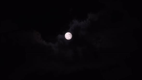 Bright Full Moon Behind Fast Moving Dark Clouds on Night Sky