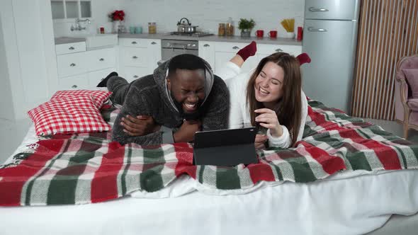 Happy Couple Laughing While Watching Video on Bed