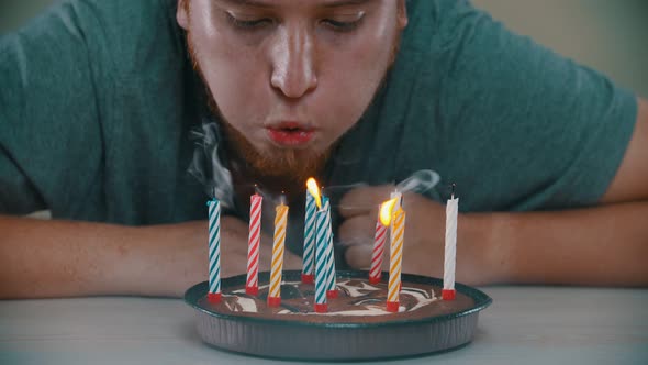 Man Is Blowing Out the Candles on the Cake