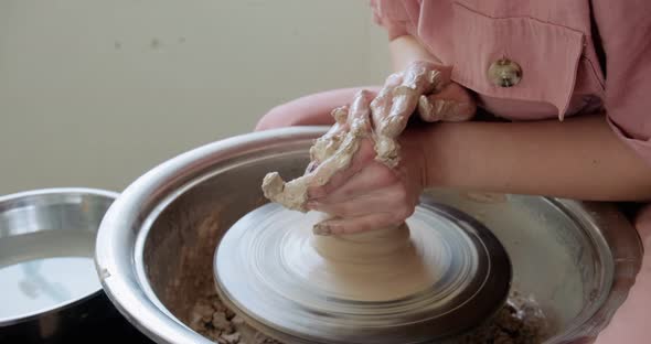 Female Potter Sitting and Makes a Cup on the Pottery Wheel. Woman Making Ceramic Item. Pottery