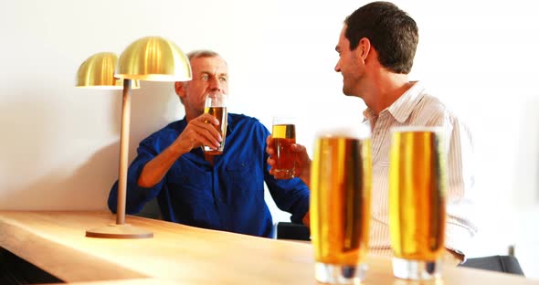 Two men interacting with each other while having beer at counter