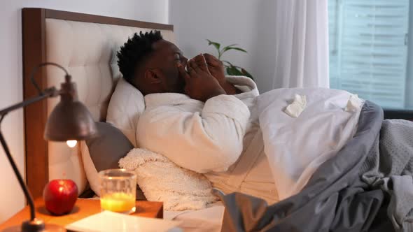 Side View Portrait of Tired Ill Young Man with Runny Nose Lying in Bed Sighing