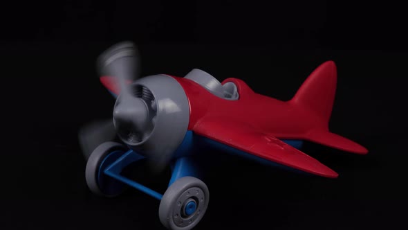The Propeller Of The Wheeled Toy Airplane Is Spinning in front of the Black Background