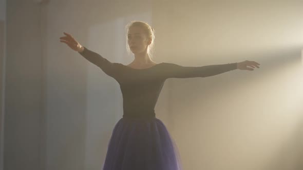 Medium Shot of Graceful Slim Ballerina in Tutu Spinning in Backlit Fog in Second and Fifth Position