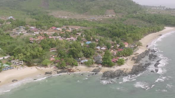 Wide aerial footage of village next to the ocean in Sierra Leone, Africa.