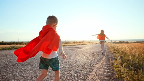 Two Running Children in Field Under Sunlight Brother and Sister Put Homemade Superheroes Costumes