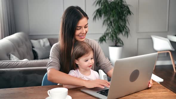 Happy Mother Chatting Typing on Keyboard Teaching Daughter Use Laptop