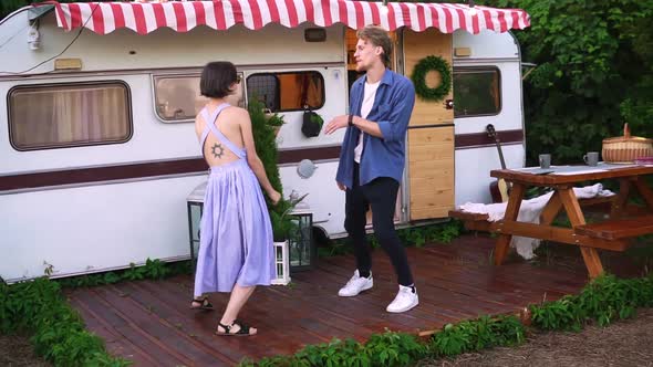 Stylish Cheerful Couple Man and Woman Smiling While Dancing Together Near House on Wheels Outdoors