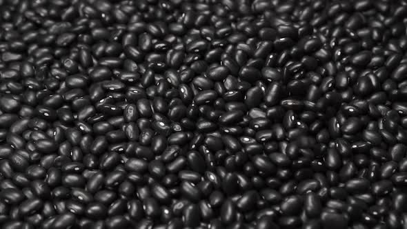 Black beans are slowly falling into a pile of legumes 