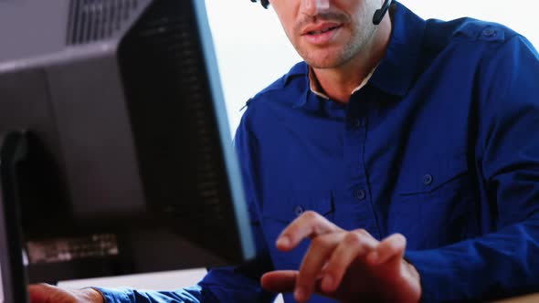 Male executive with headset working on computer